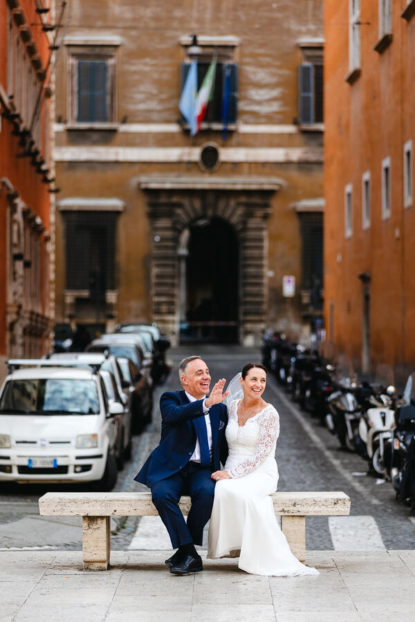 Newly-wed couple sitting on a bench along Via della Conciliazione waiwing and thanking people for the good wishes