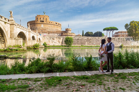 Wedding Couple in a sweet embrace on the Tiber's river bank with Castel Sant'Angelo towering in the background
