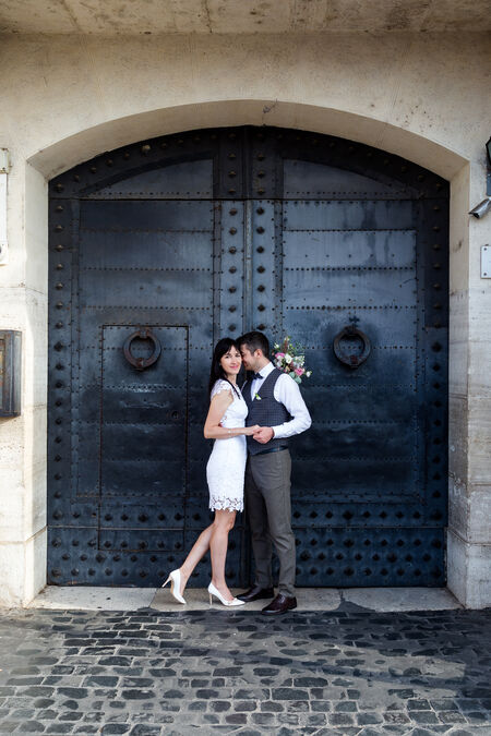 Newly-weds in a sweet embrace next to a beautiful wooden door Castel Sant'Angelo in Rome