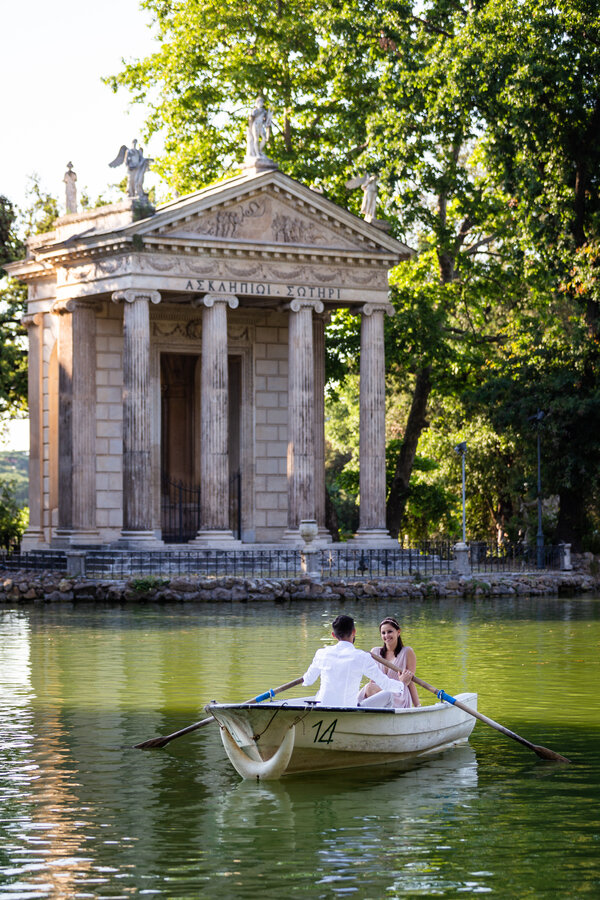 Smiling couple on a rowboat at the lake in Villa Borghese, during their honeymoon photo session.