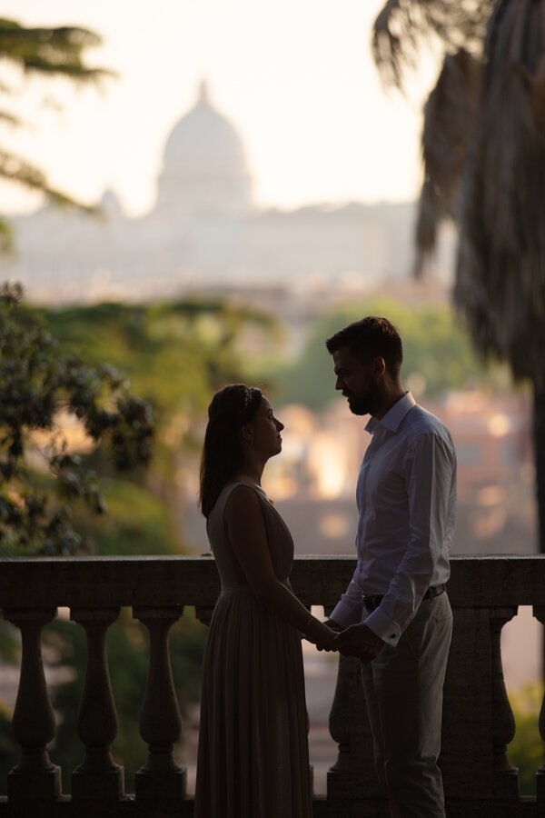 Newly-wed couple, holding hands at the Pincio Gardens, with Saint Peter's in the background.