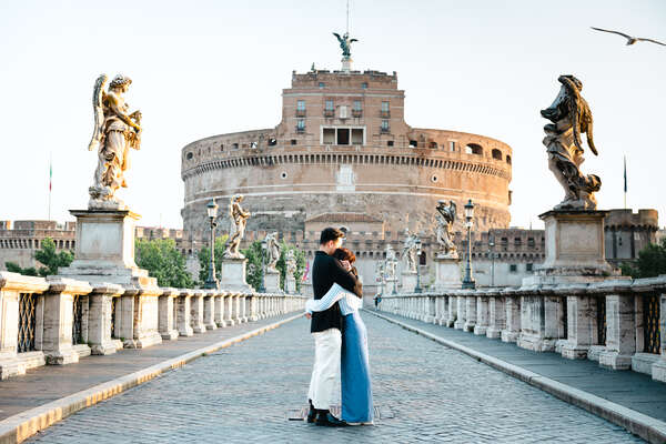 Newly-engaged couple holding each other on Castel Sant'Angelo Bridge in Rome