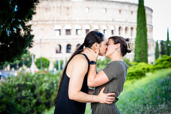 Newly-engaged same-sex couple kissing during their surprise proposal on Monte Oppio near the Colosseum in Rome