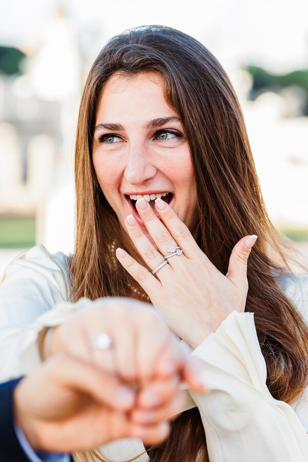 Beautiful newly-engaged woman acting surprise after receiving her engagement ring in Rome