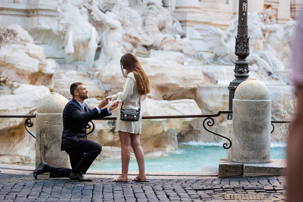 Couple during their surprise marriage proposal at the Trevi Fountain at sunrise