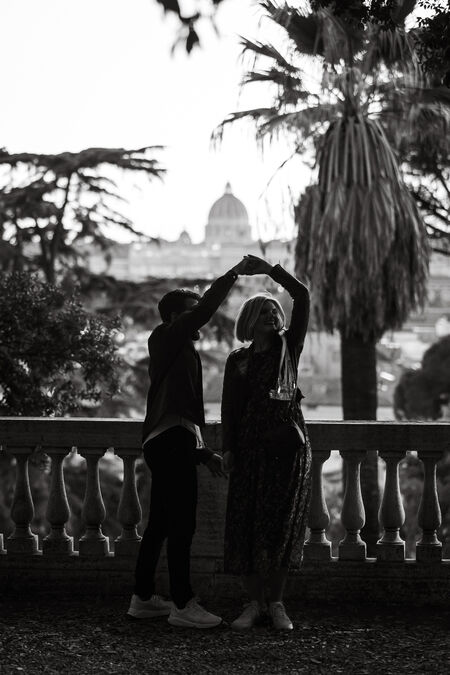 Black and white image of a newly-engaged couple dancing with the Vatican in the background