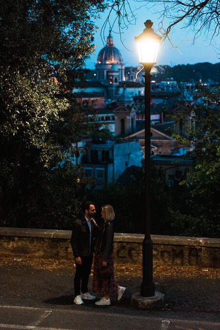 Newly-engaged couple lit by a street lamp in the blue hour in Rome
