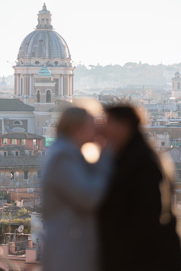 Out-of-focus newly-engaged couple kissing with the background in focus