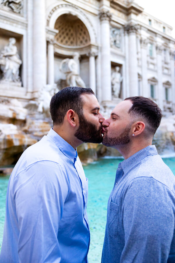 Gay couple kissing during their surprise proposal photoshoot at the Trevi Fountain in Rome