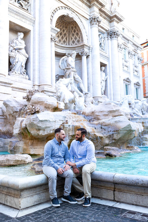Newly-engaged couple sitting by the Trevi Fountain in Rome