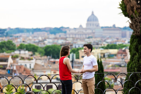 Couple holding hands on the Pincian Hill in Rome with the Vatican in the background