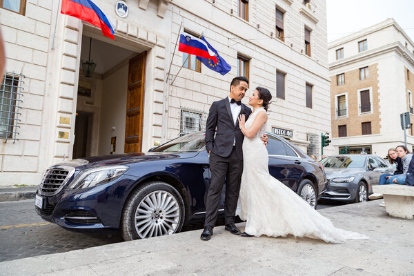 Newly-wed Sposi Novelli couple posing next to a Mercedes, in Via della Conciliazione, Rome