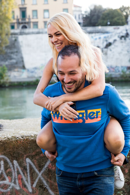 A beautiful couple on vacatino in Rome on the riverside being playful