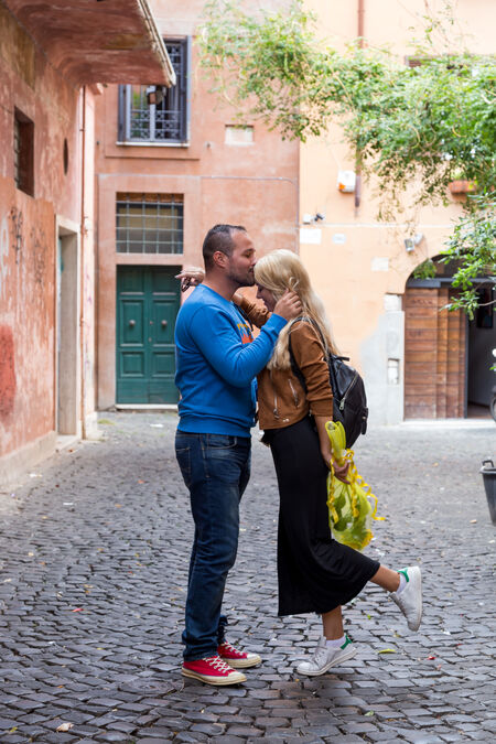 A boyfriend kissing his girlfriend on her forehead in an alley of Trastevere