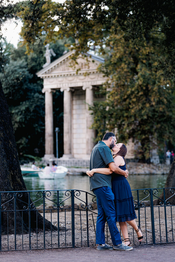 Couple holding each other with the Temple of Aesculapius in Villa Borghese during their wedding anniversary photo session in Rome