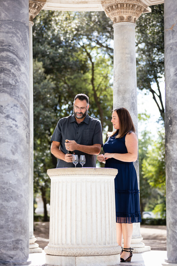 Couple celebrating their wedding anniversary under the Temple of Diana in Villa Borghese with champagne