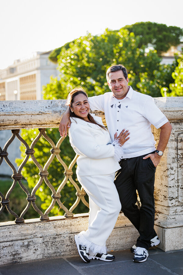 Couple holding each other and smiling for the camera on their wedding anniversary photo shoot on Castel Sant'Angelo Bridge in Rome