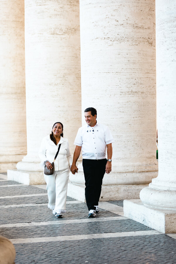 Couple walking under the Saint Peter's Square colonnade during their wedding anniversary photo shoot in Rome
