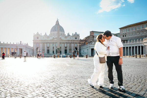 Couple holding each other with the Vatican in the background during their wedding anniversary photo shoot in Via della Conciliazione in Rome
