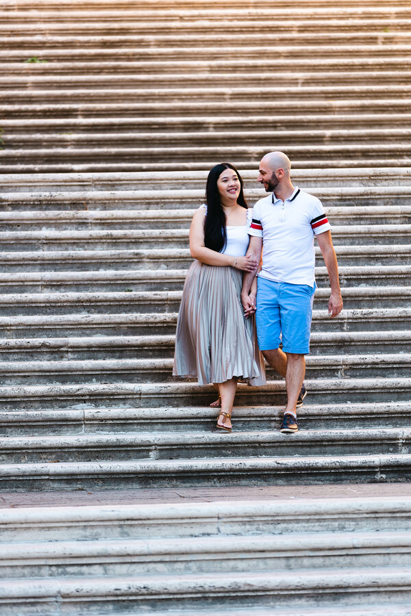 Newly-engaged coupel walking down the stairs at the Capitoline Hill during their engagement photo session in Rome