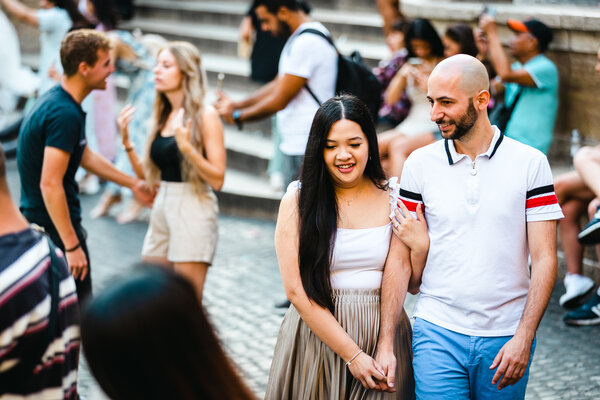 Happy newly-engaged couple walking by the Trevi Fountain during their engagement photo shoot in Rome