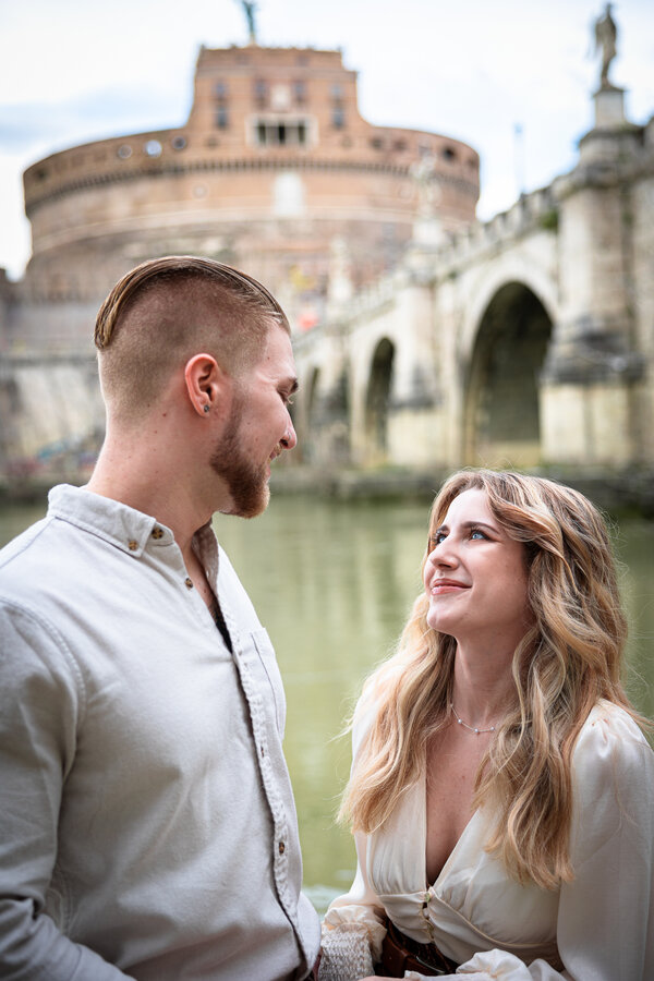 newly-engaged couple looking at each other romantically with Castel Sant'Angelo in the background