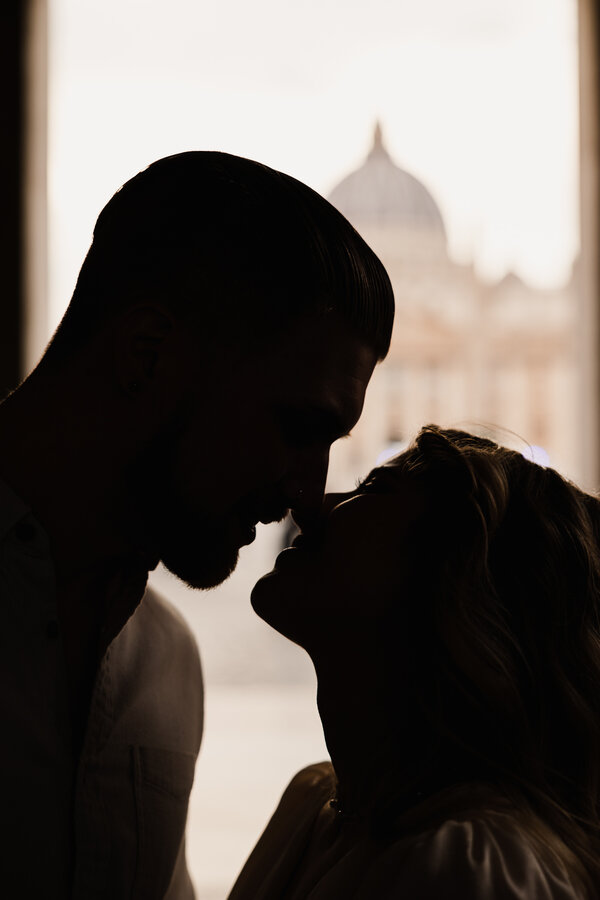 Silhouette of a newly-engaged couple kissing with the Basilica of San Pietro in the background