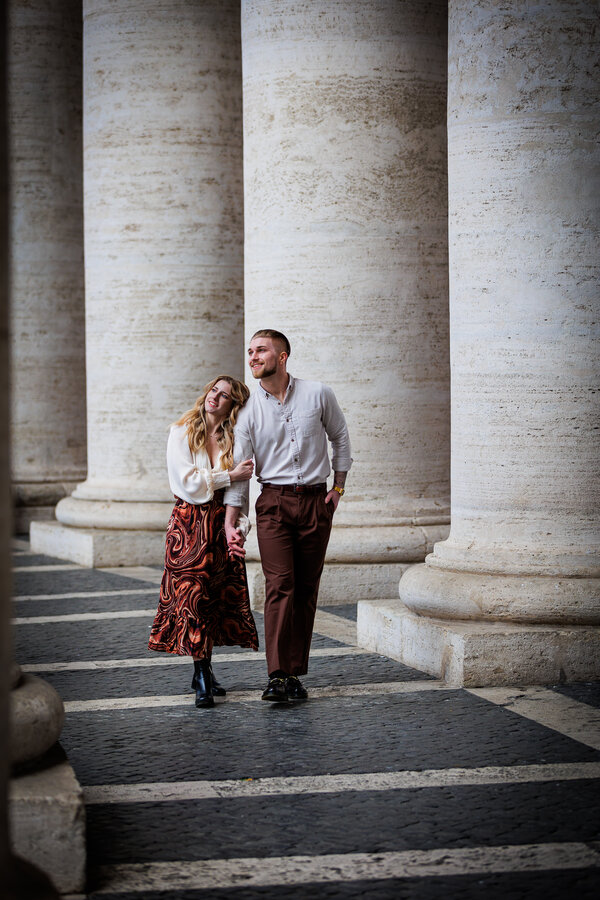 Newly-engaged couple walking under the colonnade in Saint Peter's Square during their engagement photoshoot in Rome