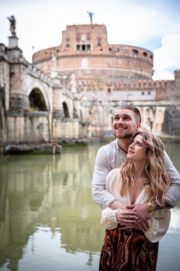 Young newly-engaged couple on the Tiber riverback near Castel Sant'Angelo in Rome