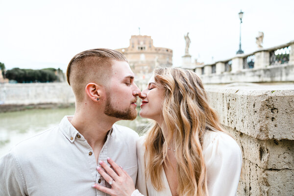 Couple kissing on Castel Sant'Angelo Bridge during their engagement photoshoot in Rome