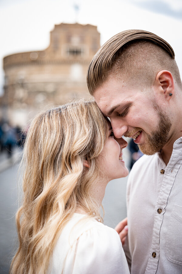 Beautiful young couple on Castel Sant'Angelo Bridge during their engagement photo session in Rome