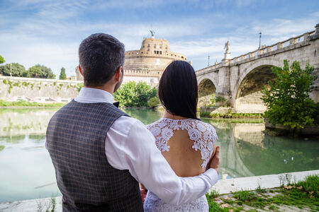 Newly-weds looking at the beautiful Castel Sant'Angelo from the riverbank