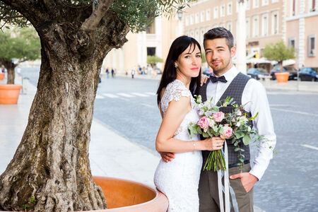Newly-wed Anastasia and Dmitry in Via della Concilizione under an olive tree during their destination wedding photo shoot