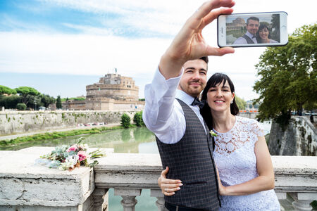 An image of a newly-wed couple taking a beautiful selfie, at the end of a destination wedding photo shoot in Rome