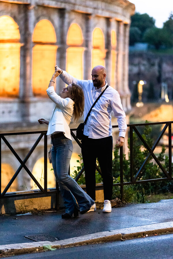 Newly-engaged couple dancing with the Colosseum in the background