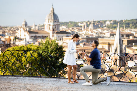 Man offering an engagement ring during a surprise marriage proposal on the Terrazza Belvedere in Rome