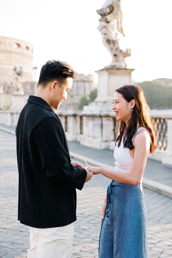 Newly-engaged couple in Rome on Castel Sant'Angelo Bridge during their surprise wedding proposal shoot in the early morning