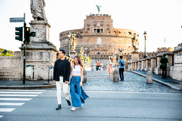 Newly-engaged couple crossing the road with Castel Sant'Angelo in the background