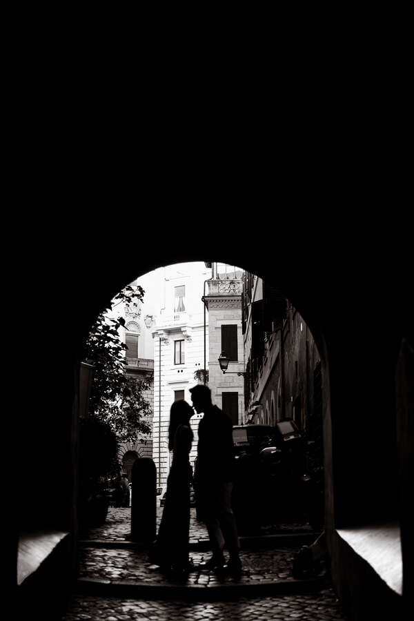 Newly-engaged couple in silhouette kissing near Castel Sant'Angelo during their surprise wedding proposal photoshoot