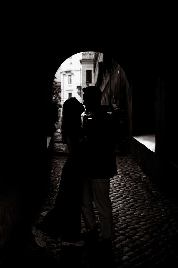 Newly-engaged couple in silhouette kissing during their surprise proposal photoshoot near Castel Sant'Angelo