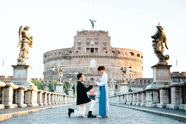 Charming couple during their surprise marriage proposal photoshoot in Rome on Castel Sant'Angelo Bridge early in the morning