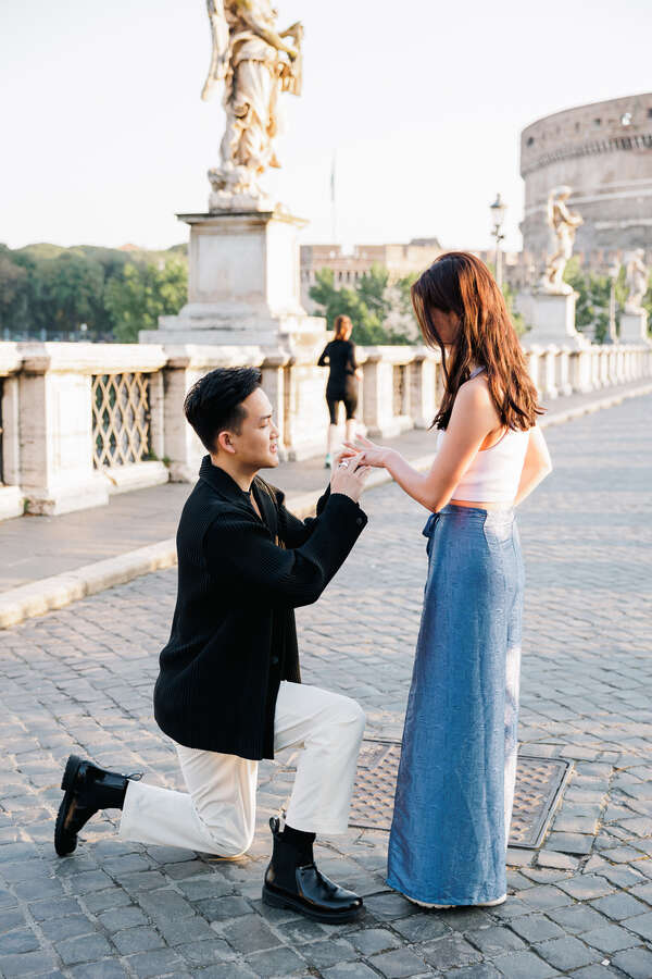 Couple during their surprise wedding proposal photoshoot in Rome while putting on the engagement ring