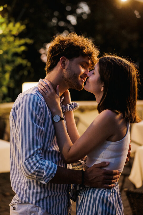 Newly-engaged couple kissing during their sunset surprise proposal photo session in Rome