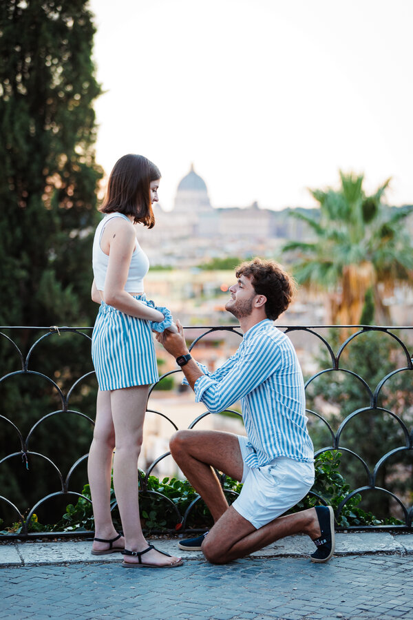 Young couple during a surprise wedding proposal at sunset on the Terrazza Belvedere in Rome