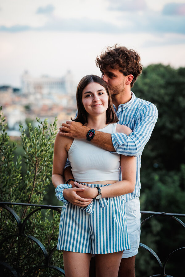 Portrait of beautiful young newly-engaged couple on the Terrazza Belvedere with the Vittoriano in the background at sunset