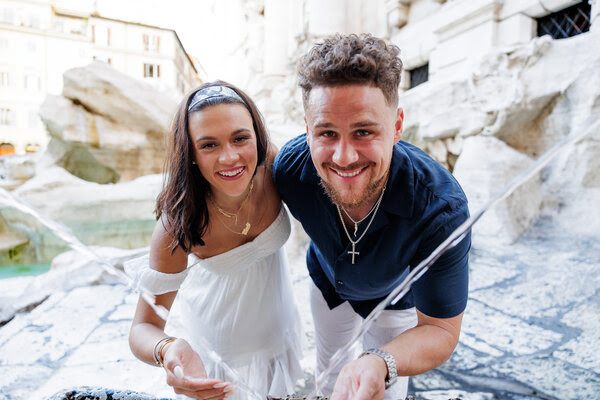 Newly-engaged couple drinking water at the Trevi Fountain in Rome
