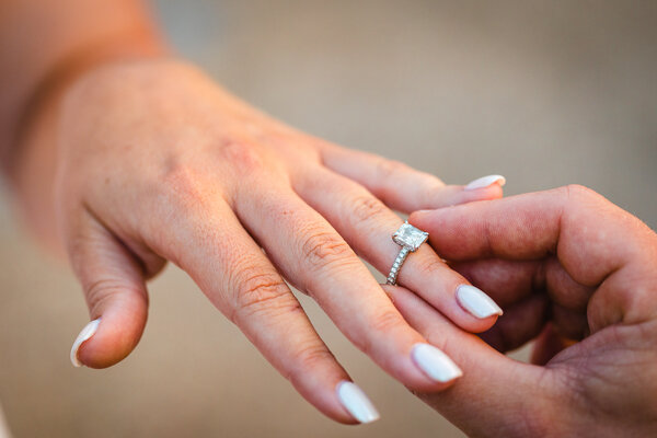 Close-up of woman's hand during the engagement ring fitting during a wedding proposal photo session