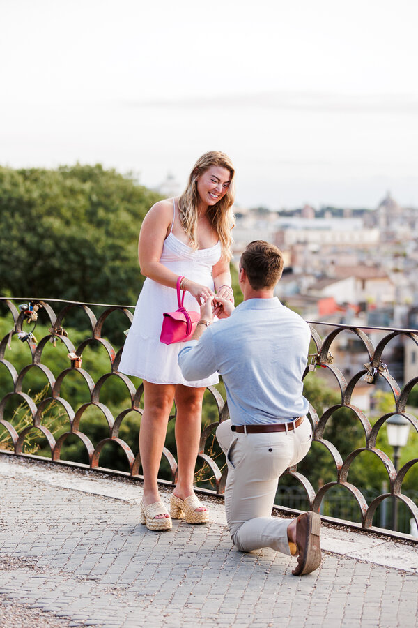 Fiancé putting on the engagement ring on her fiancée during their surprise wedding proposal in Rome