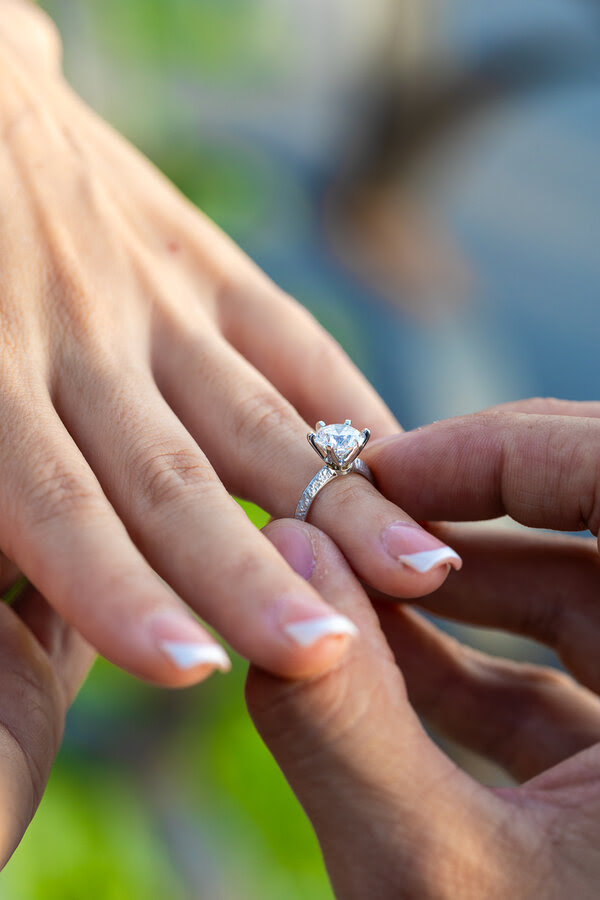 Detail of a diamond engagement ring on a woman's finger during a marriage proposal photoshoot in Rome