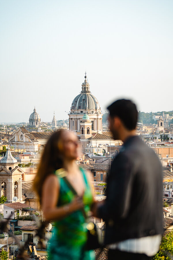 Couple holding each other out of focus with Rome at sunset in the background